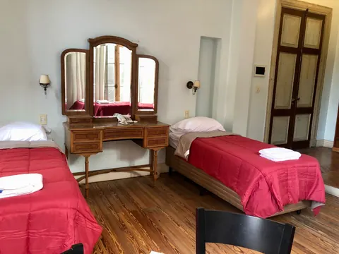 Habitación doble de la residencia, con dos camas, tocador con espejo y piso de madera